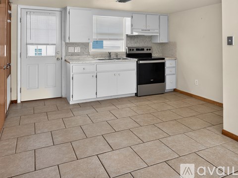 A kitchen with white cabinets and a tile floor.
