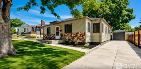 A beige house with a brown fence and a tree in front.