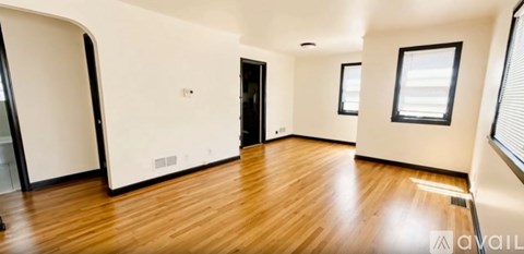 A spacious room with wooden floors and white walls.