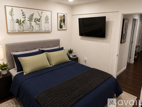 A bedroom with a large bed and a flat screen TV mounted on the wall.