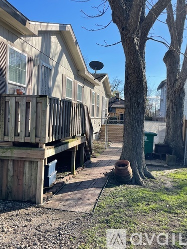A wooden deck leads to a house with a satellite dish on the roof.