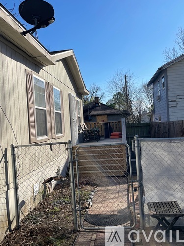 A backyard with a fence and a satellite dish on the house.