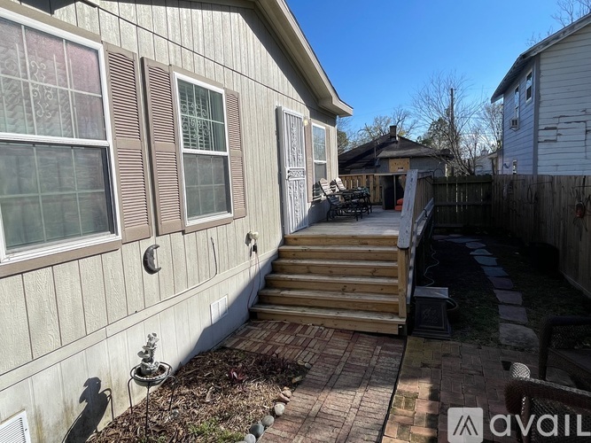 A house with a wooden deck and a small tree in a pot.