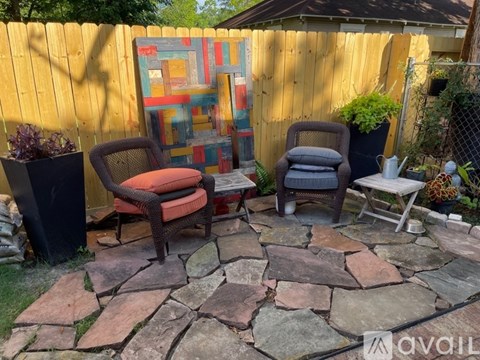 A patio with a stone floor and two chairs.