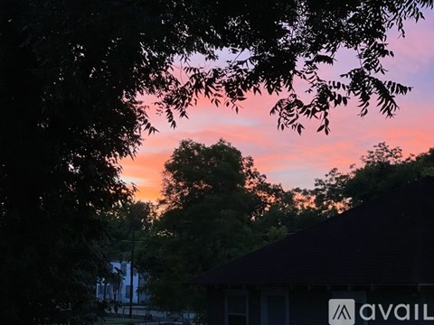 A house with a sign that says "AVAIL" is seen through the branches of a tree.