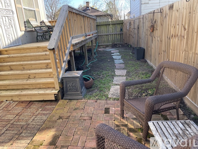 A backyard with a chair, table, and a small garden.