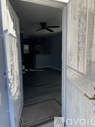A room with a ceiling fan and a rug on the floor.
