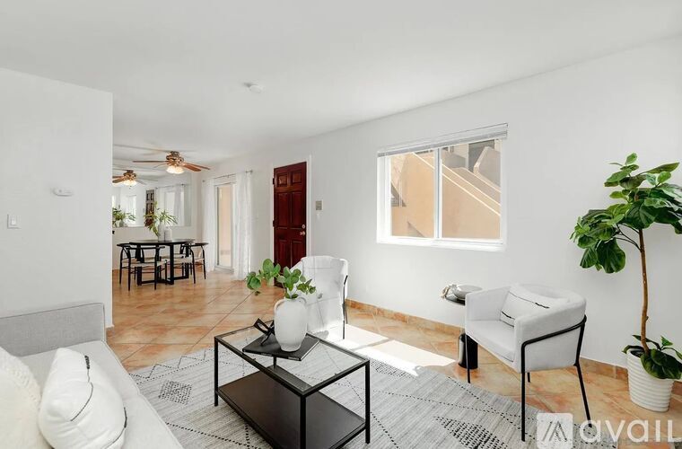 A living room with a white couch, a black coffee table, and a white chair.