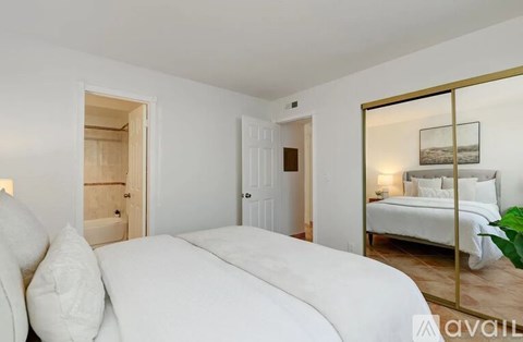 A bedroom with a large bed and a mirrored dresser.