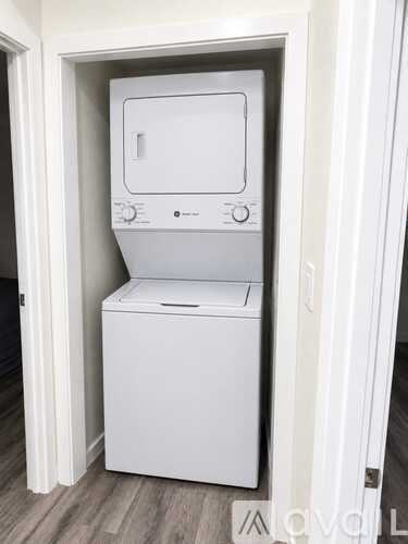 A white dishwasher and microwave are stacked on top of each other in a small space.