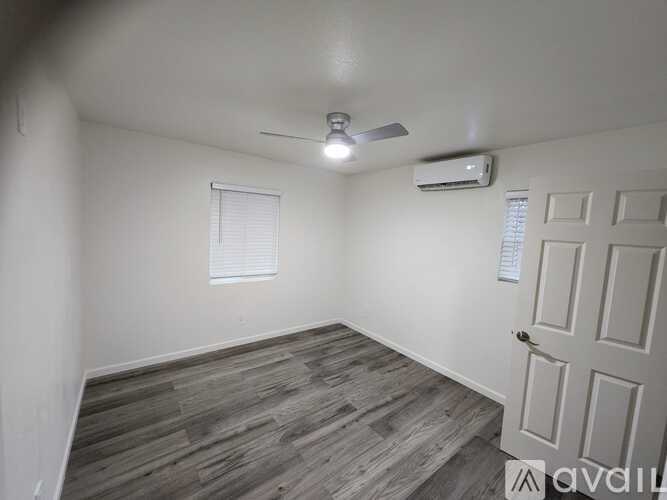 A room with a ceiling fan and a window with blinds.