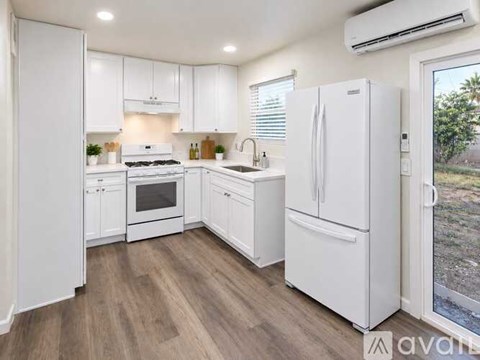 A white kitchen with wooden floors and white appliances.