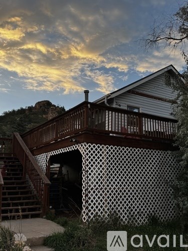 A house with a wooden deck and a staircase leading to the entrance.