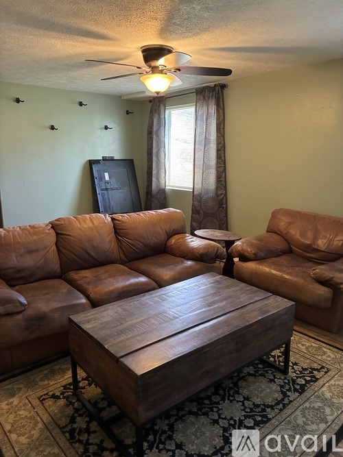 A living room with a brown leather couch and a wooden coffee table.