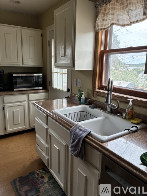A kitchen with a white sink and cabinets.