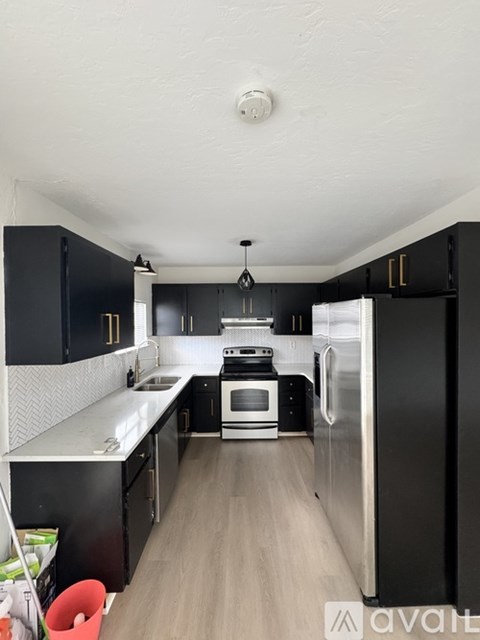 A kitchen with black cabinets and a stainless steel refrigerator.