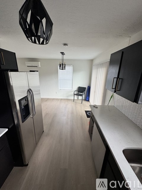 A kitchen with black cabinets and a stainless steel refrigerator.