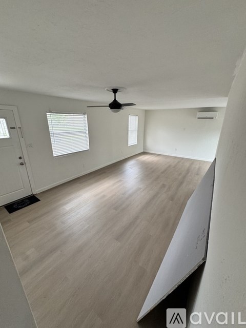 A room with a ceiling fan and wooden flooring.