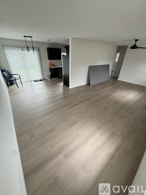 A spacious room with wooden flooring and a ceiling fan.