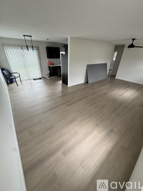 A spacious room with wooden flooring and a ceiling fan.