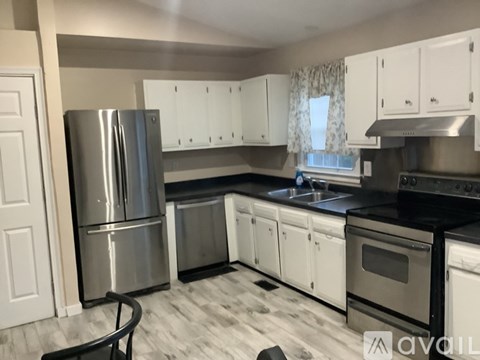A kitchen with white cabinets and a stainless steel refrigerator.