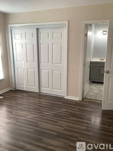 A room with a white door and a brown floor.