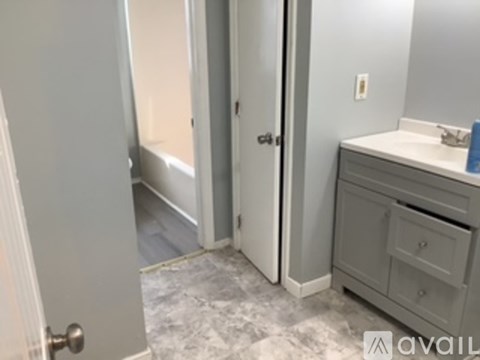 A bathroom with a sink, mirror, and a door.