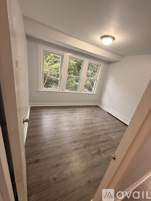 A room with wooden flooring and a window overlooking trees.