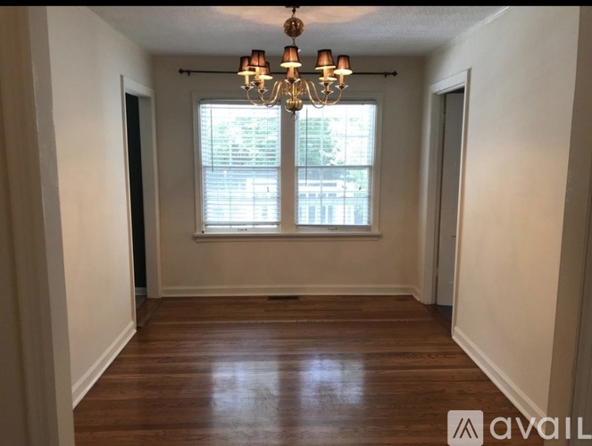 A room with a chandelier and a window with blinds.