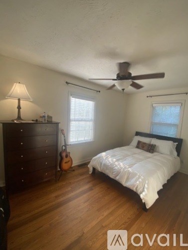 A bedroom with a bed, dresser, and guitar.