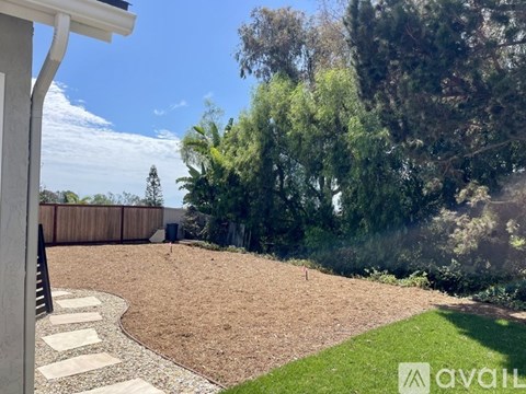 A backyard with a sandy area and a green lawn.