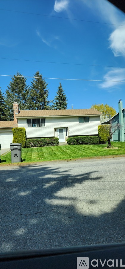 A house with a green lawn and a tree in front of it.