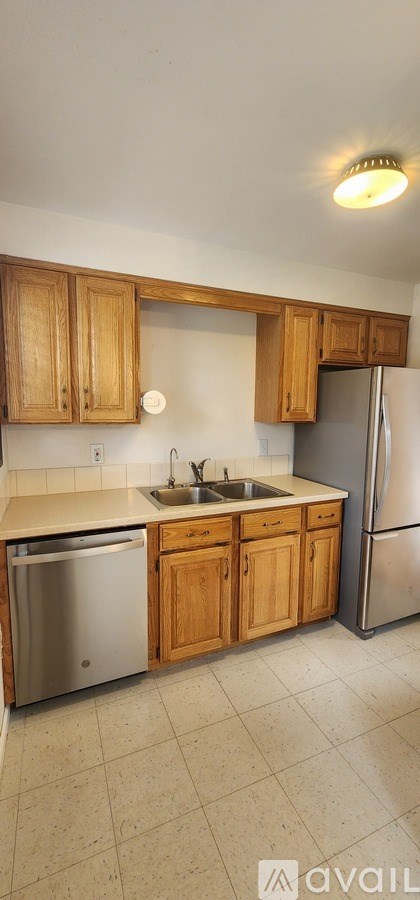 A kitchen with wooden cabinets and a stainless steel refrigerator.