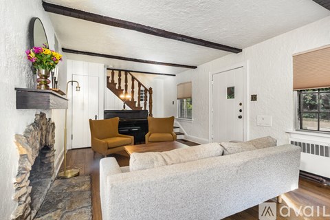 A living room with a grey couch and a stone fireplace.