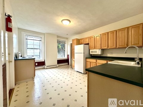 A kitchen with a black counter top and white tiled floor.