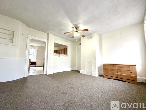A spacious room with a ceiling fan and a carpeted floor.