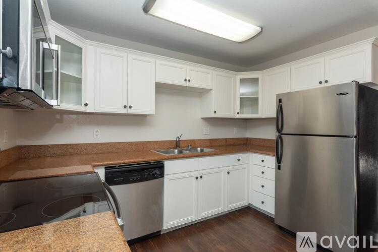 A kitchen with white cabinets and a stainless steel refrigerator.