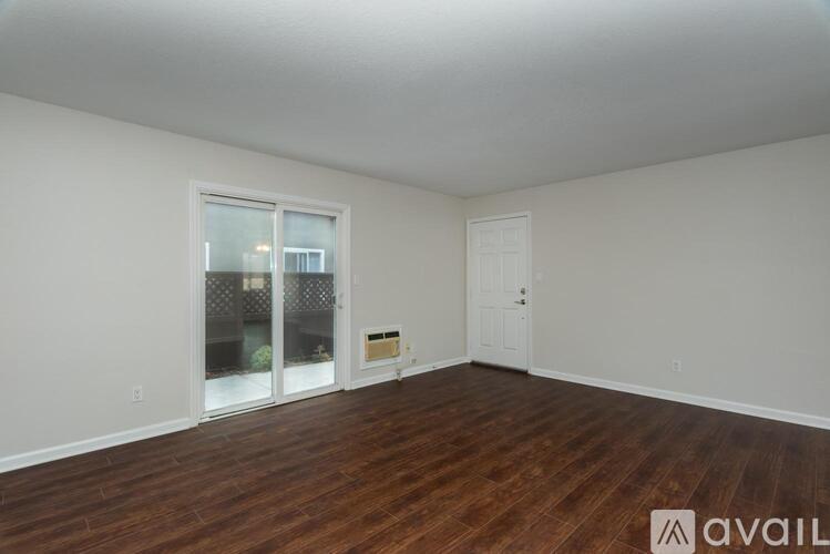 A room with wooden floors and a white door is available for rent.