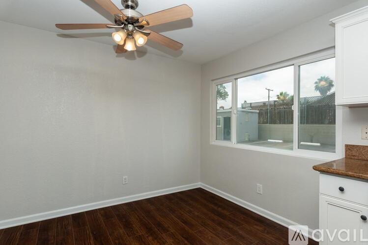 A room with a ceiling fan and wooden floors.