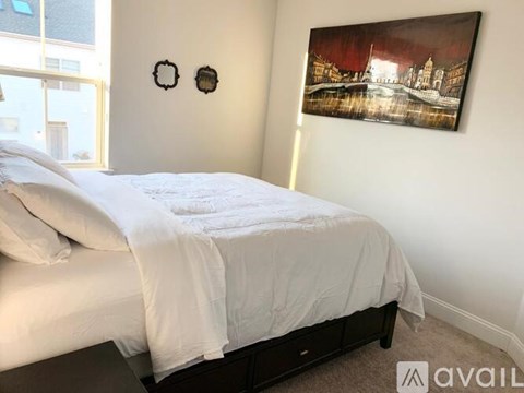 A bedroom with a large bed and a painting on the wall.
