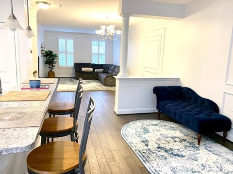 A living room with a blue couch and a dining table with chairs.