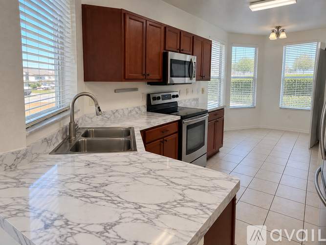 A kitchen with brown cabinets and a marble countertop.