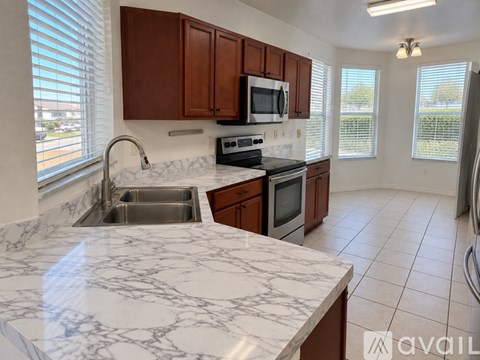 A kitchen with brown cabinets and a marble countertop.