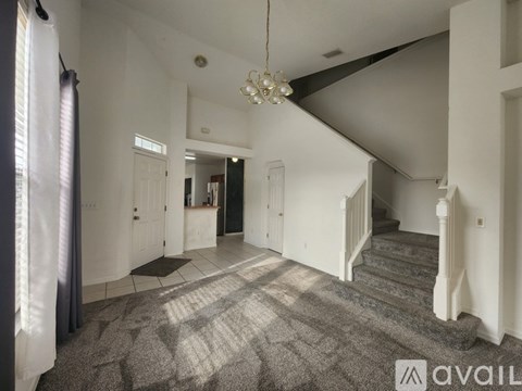 A spacious room with a carpeted floor and a staircase leading to another room.