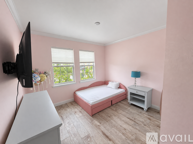 A bedroom with a pink wall and a bed with a white mattress.
