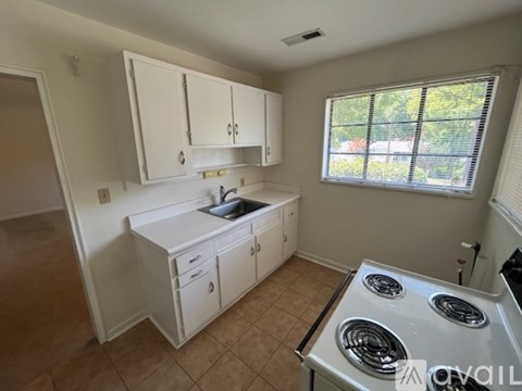 A small kitchen with a sink, stove, and cabinets.