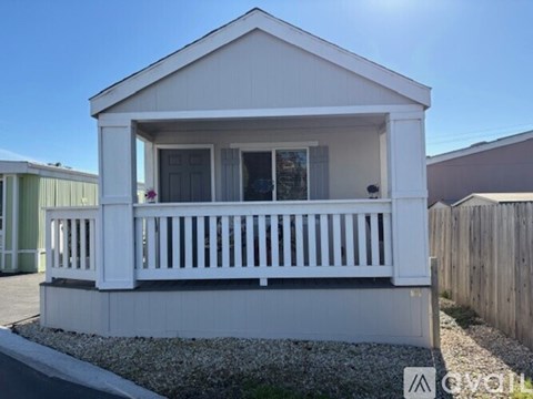 A small white house with a porch and a balcony.
