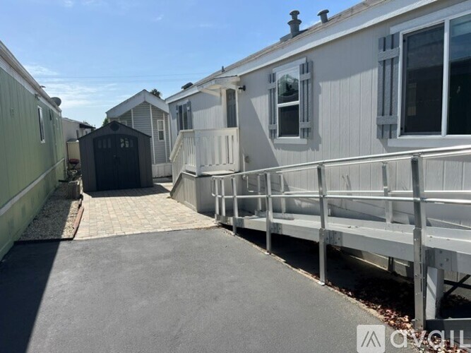 A row of mobile homes with a concrete walkway in the foreground.