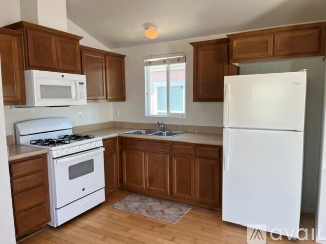 A kitchen with white appliances and wooden cabinets.