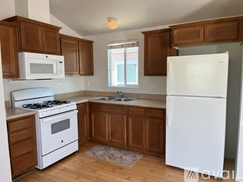 A kitchen with white appliances and wooden cabinets.